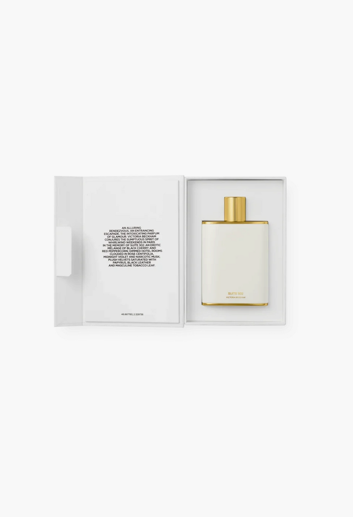 GLAM MODA Suite 302 Eau de Parfum in a white enamel bottle with gold cap, presented in an open gift box.