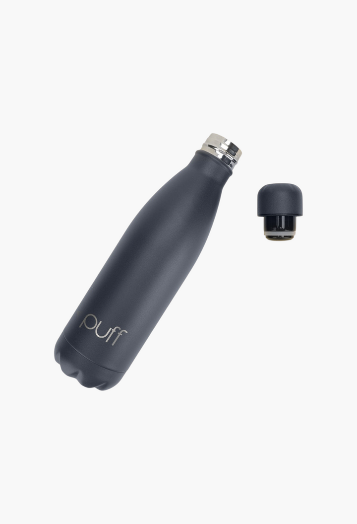 GLAM MODA matte Mykonos blue stainless steel Puff Bottle with a spill-resistant cap on a light yellow background.