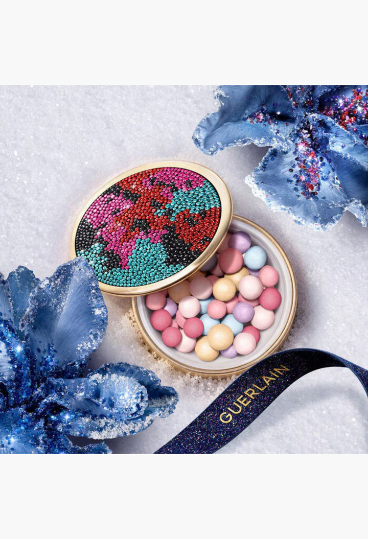 GLAM MODA Météorites setting and finishing powder pearls in a rhinestone-encrusted case on a snowy background.