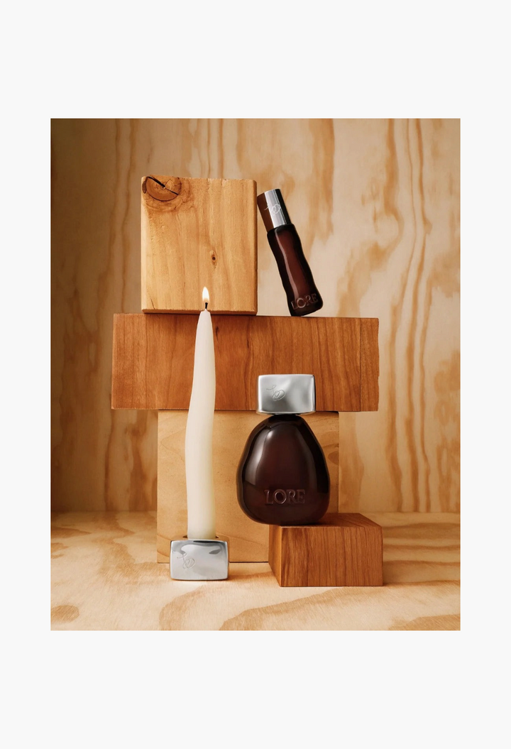 GLAM MODA Somewhere but nowhere fragrance set featuring perfume bottles and a taper candle on wooden blocks