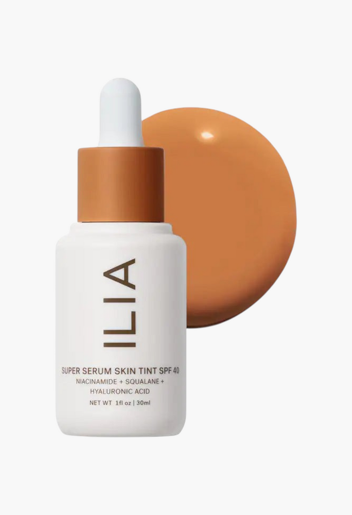 GLAM MODA ILIA Super Serum Skin Tint SPF 40 liquid foundation bottle with a swatch of tan makeup on a white background
