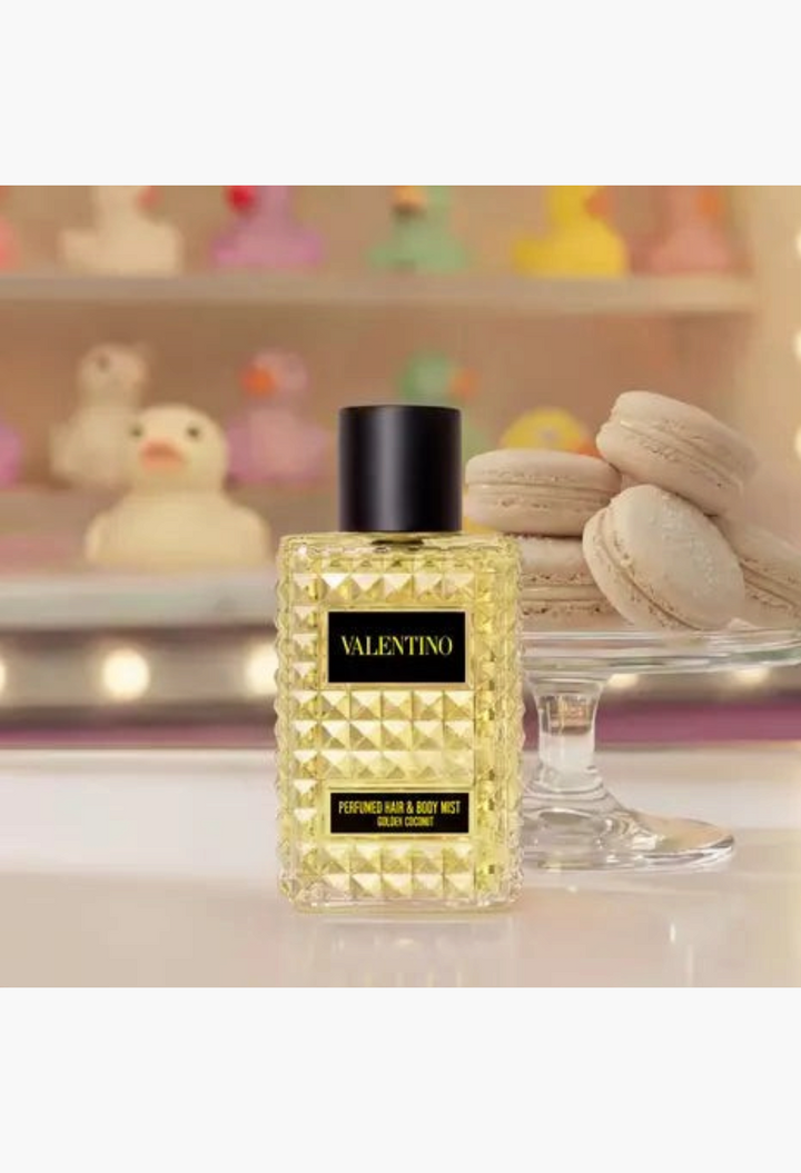 GLAM MODA Valentino Born In Roma Golden Coconut hair and body mist in a glass bottle next to a stack of macarons