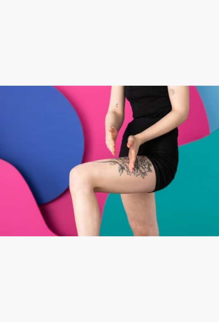 GLAM MODA Wiccy Magic Muscles massage bar being used on a leg with floral tattoo against a colorful abstract background